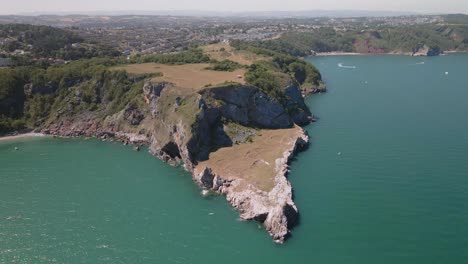 aerial wide shot showing beautiful coastline of england, atlantic ocean and city in background during sunny and cloudy day