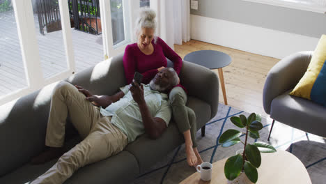 mixed race senior couple using smartphone in the living room at home