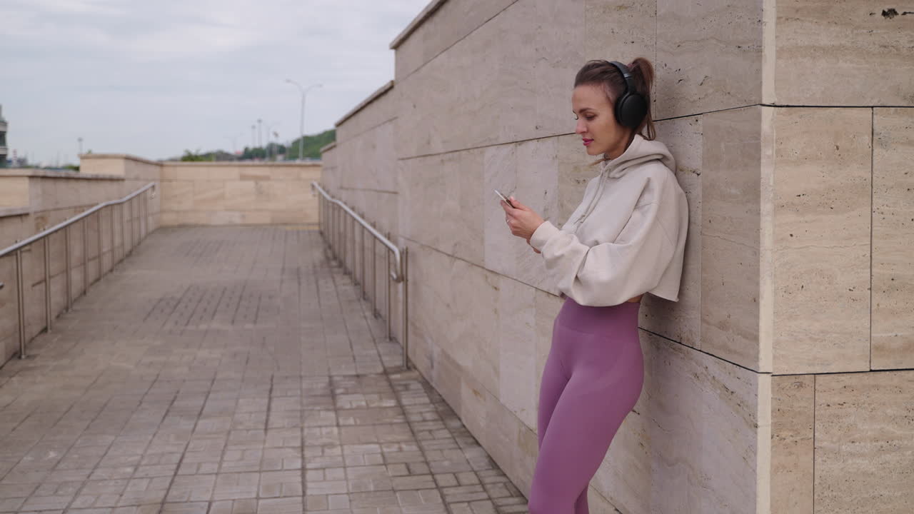 mujer usando el teléfono mientras escucha música al aire libre