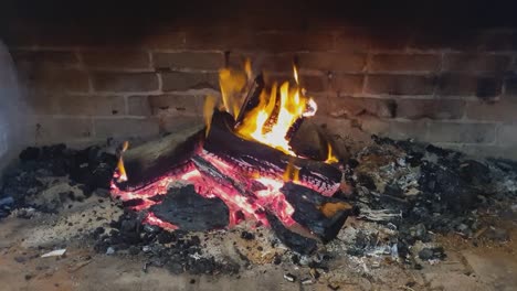 Logs-burn,-red-embers-and-glowing-flames-in-fireplace