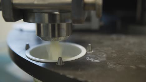 closeup on rotating automated yogurt production line pouring into pots