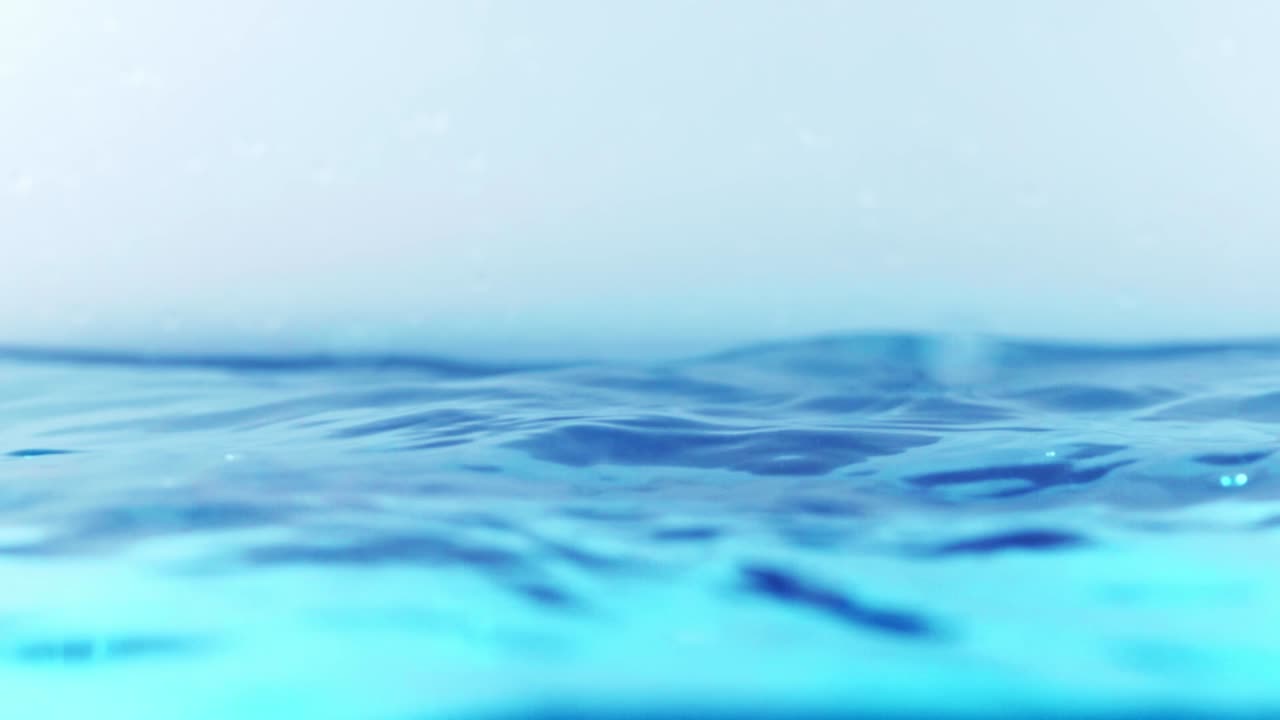 슬로우 모션의 깨끗한 물 표면은 물이 튀는 상점으로 화면을 채우고 기포로 액체 표면을 흔들고 있습니다.