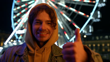 happy man showing thumbs up in city center. smiling guy looking camera.