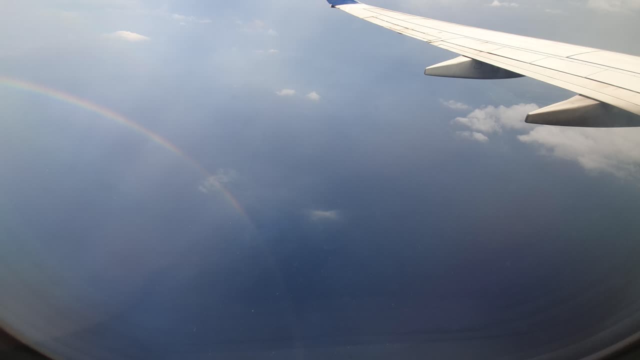 푸른 하늘과 무지개를 배경으로 한 비행기 날개
