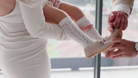 parents helping toddler put on white socks and shoes before a special event