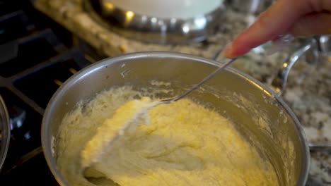 stirring a sauce pan full of creamy, cheesy grits - shrimp and grits meal