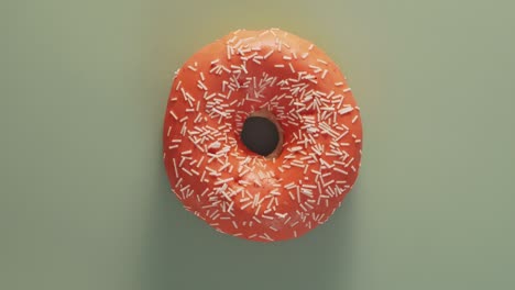 orange glazed donut rotating on blue, top view