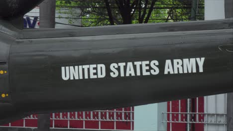 a close-up shot of the side of a military helicopter or aircraft. the white text "united states army" stenciled clearly on the dark, olive-green metal fuselage