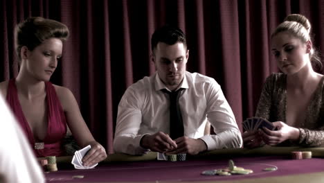 Man-playing-poker-with-two-girls