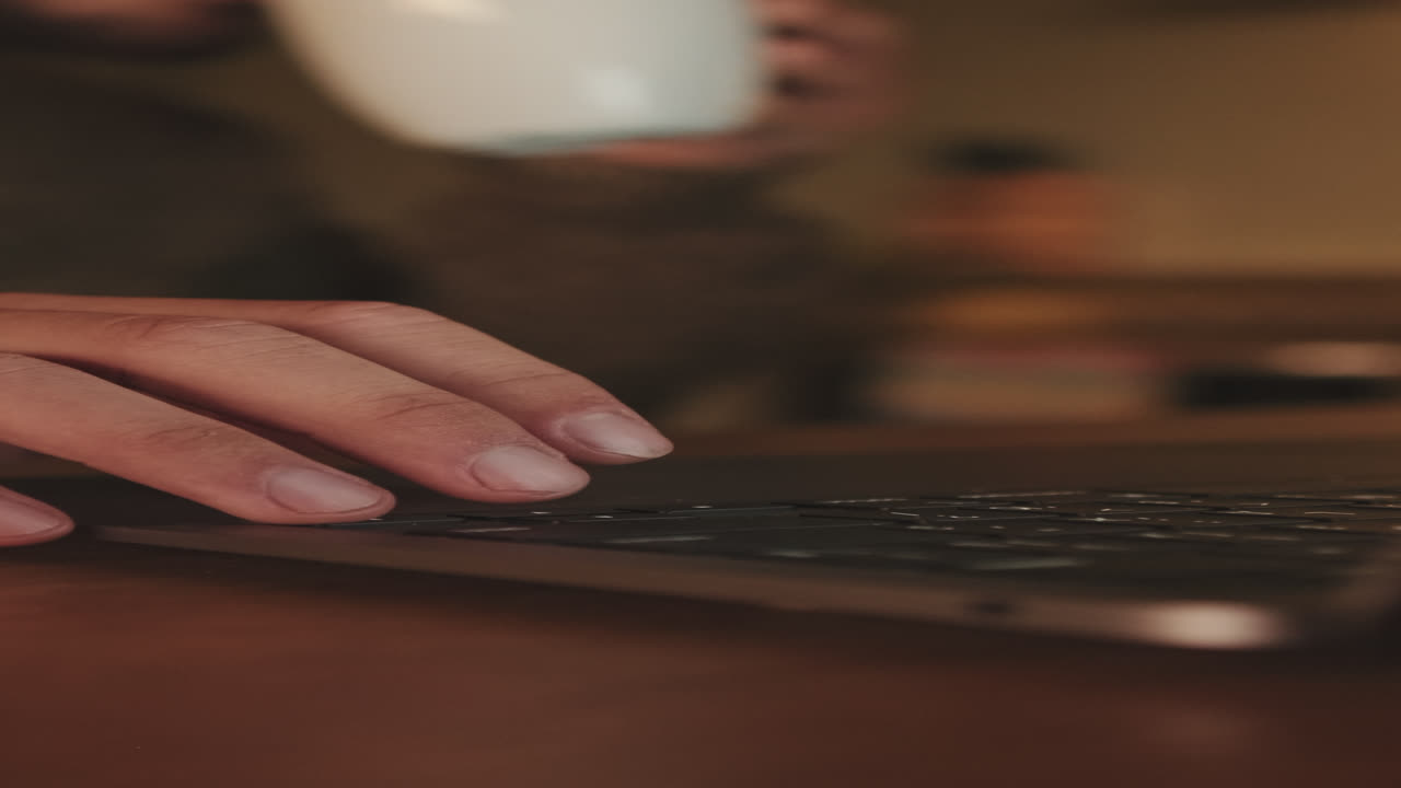 Typing on a laptop with coffee nearby