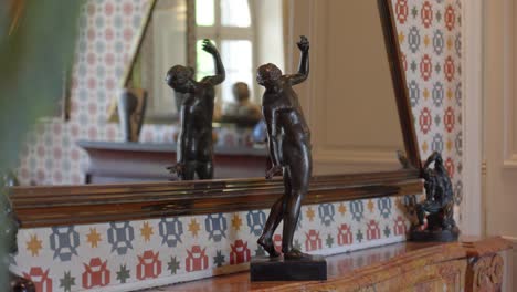 Slow-revealing-shot-of-a-posed-statue-ornament-placed-on-a-fireplace-within-the-Chateau-de-Castille