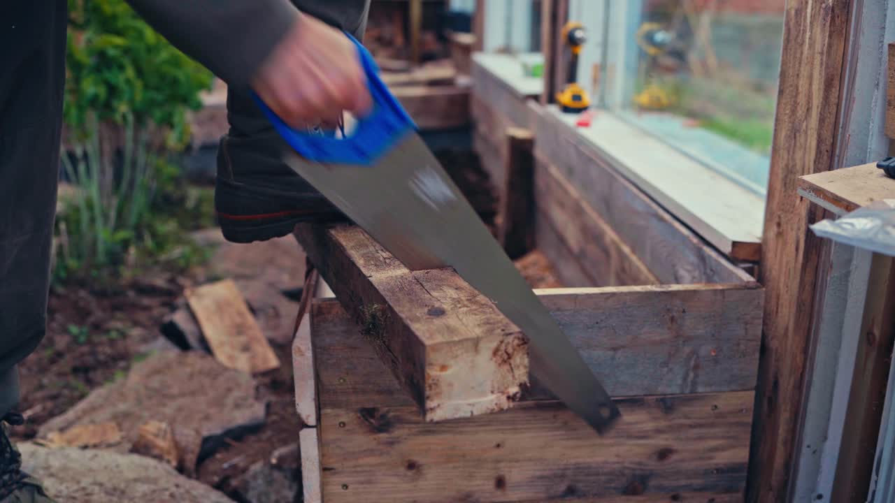 Person Cutting A Block Of Wood Using A Saw, Closeup Of Hands