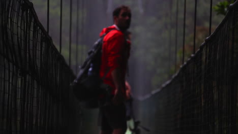 young male explorer walking on suspension bridge in rain forest trekking path exploring central america jungle in costa rica