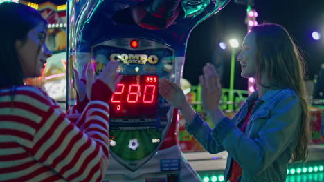 two friends hang out at funfair machine. smiling girls playing in amusement park