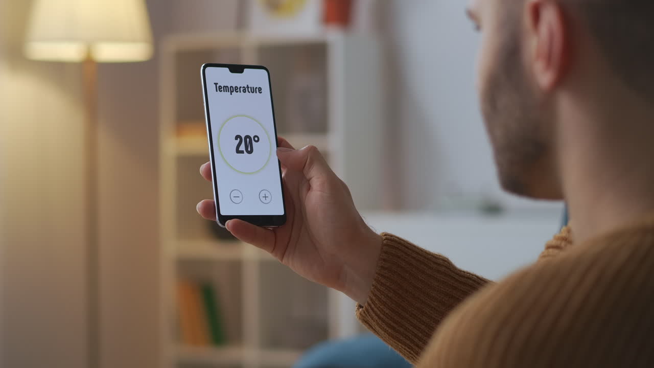 el hombre está controlando y ajustando el sistema de hogar inteligente por aplicación en el teléfono inteligente vista de primer plano del gadget en manos masculinas tecnología moderna para la comodidad
