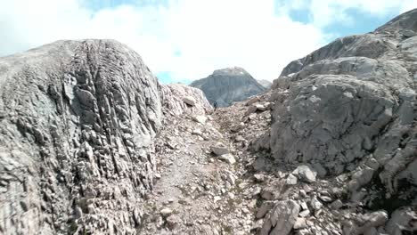 Person-hiking-while-the-drone-is-passing-through,-letting-you-see-a-big-remote-valley-starting-from-a-blue-lagoon