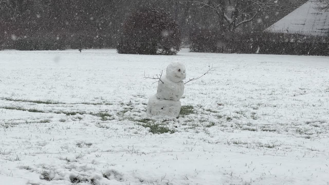 冬の屋外の楽しみ：公園の景色の中、小枝の腕を持つ小さな雪だるま