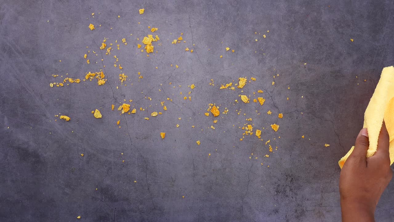 Cleaning crumbs on a table with a rag