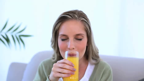 woman sat on couch showing her glass of orange juice