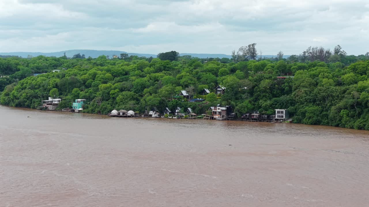 Lush riverside houses in Puerto Lagier, Misiones under cloudy skies