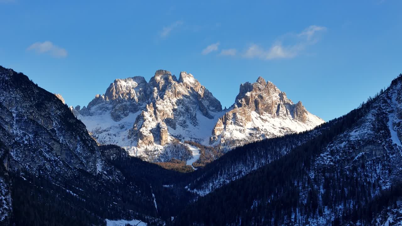 3x zoom of rock formation in the Italian Dolomites covered in snow during a sunny day (drone footage)