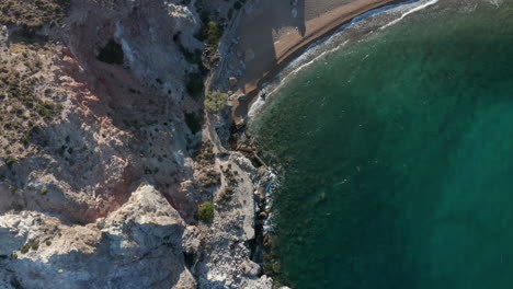 Langsame-Top-down-antenne-Entlang-Der-Generischen-Küste-Und-Des-Strandes-Mit-Türkisfarbenem-Wasser-Und-Wellen,-Die-Bei-Sonnenuntergang-Auf-Felsen-Auf-Der-Griechischen-Insel-Krachen