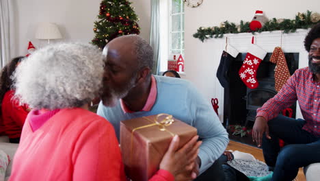 senior couple exchanging gifts as they celebrate christmas at home with family