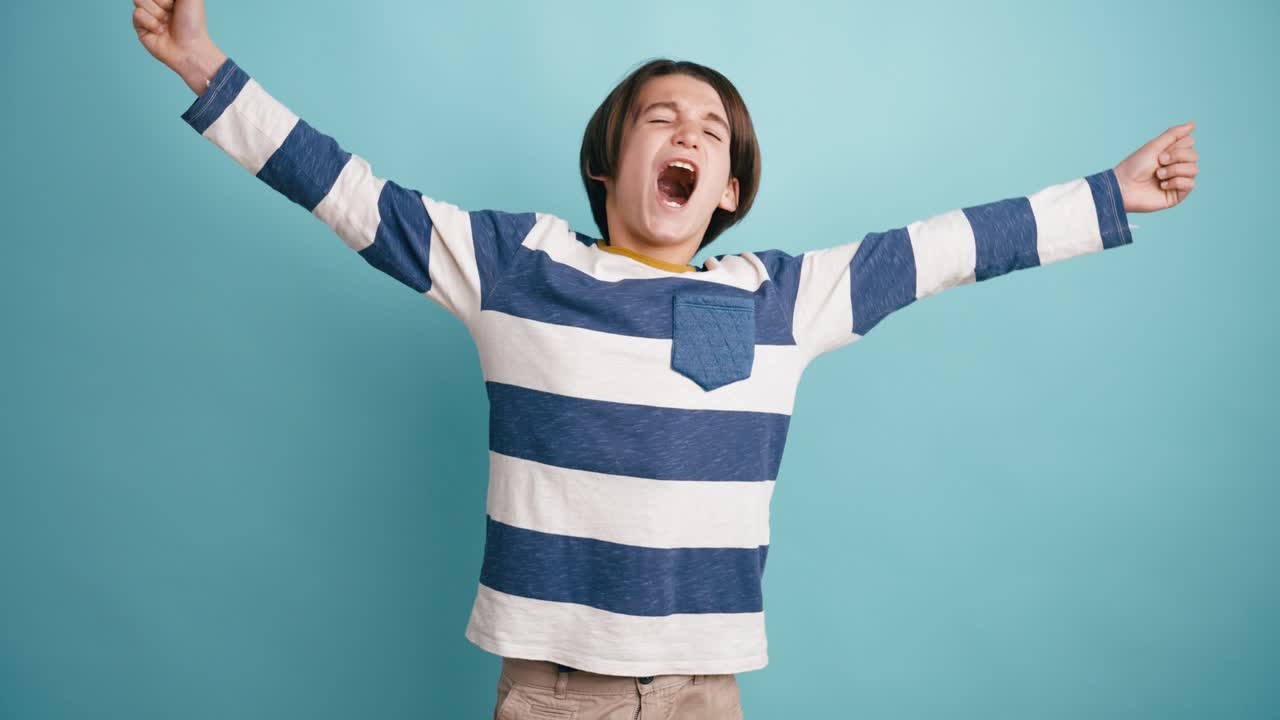 Young Boy Yawning and Stretching Against a Blue Background