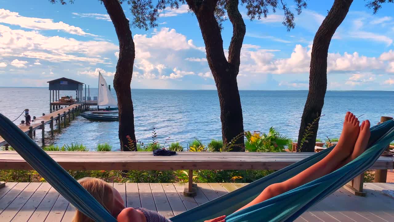 una niña se balancea suavemente en una hamaca mientras se relaja junto al agua
