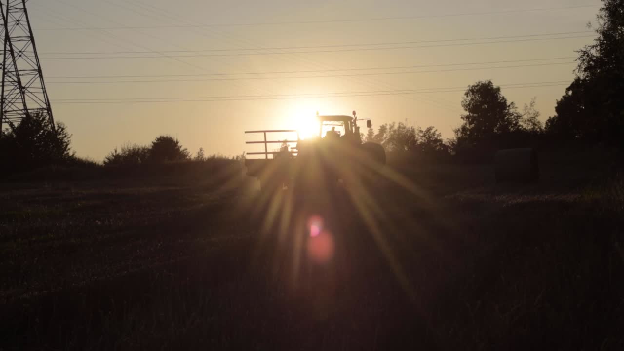 silueta de un granjero subiendo un tractor estacionario al atardecer