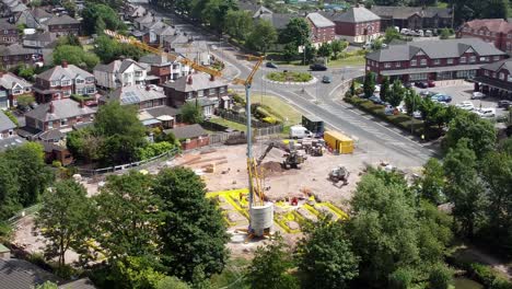 grúa alta estableciendo cimientos de edificios en el vecindario de la ciudad británica vista aérea sobre los techos de las casas suburbanas, toma estática