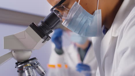 primer plano de una trabajadora de laboratorio o flebotomista analizando muestras de sangre en el laboratorio con microscopio