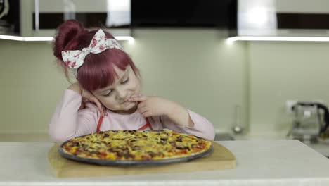 cooking pizza. little child in apron with freshly baked hot pizza in kitchen