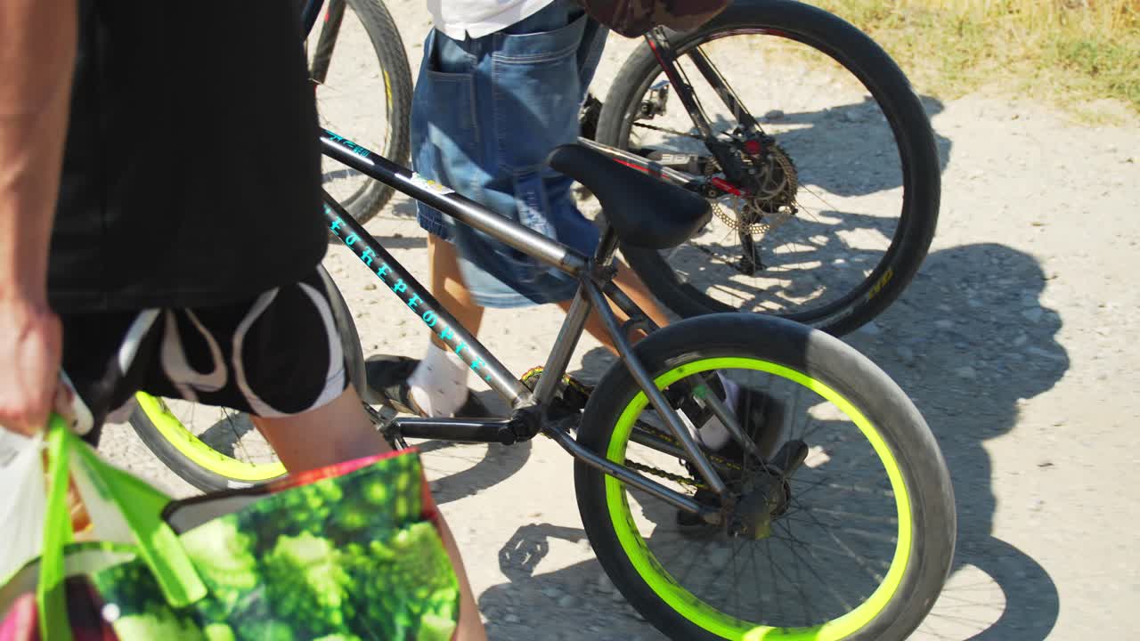 자전거 2대, 산악 자전거 1대, bmx 1대를 들고 있는 사람들, 다리만 보입니다.