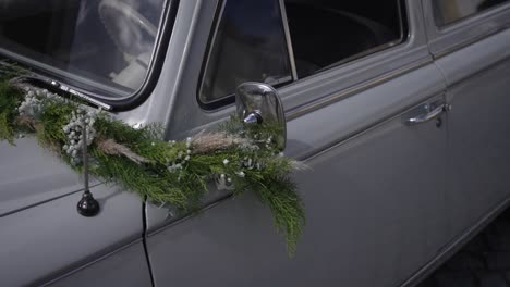 classic vintage car door adorned with green garland and berries for wedding celebration