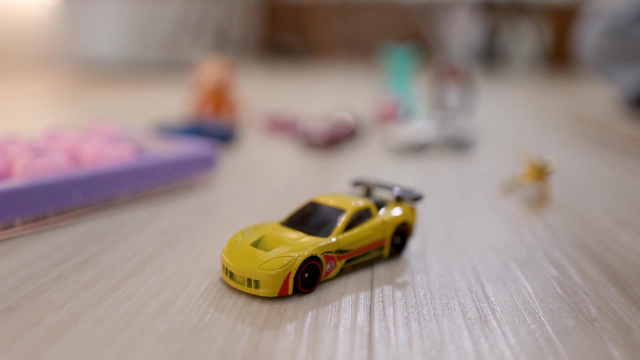 A close up view focuses on a bright yellow miniature toy car resting indoors.