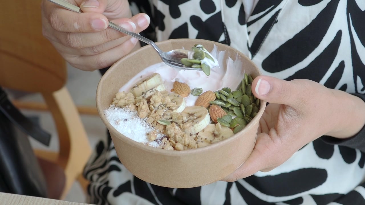 Persoon houdt een gezonde yoghurtkom met toppings vast