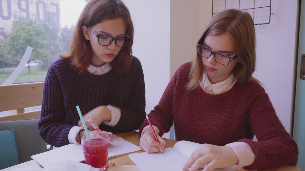dos chicas estudiando en un café