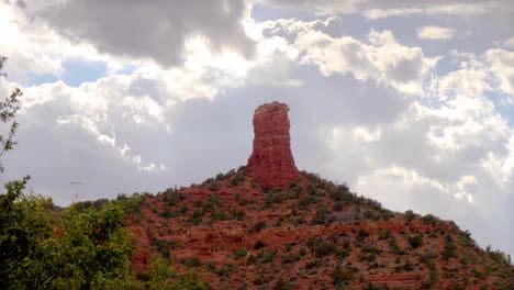 Panning-view-of-majestic-glowing-clouds-behind-a-chimney-formation-of-red-rock-in-Sedona,-Arizona