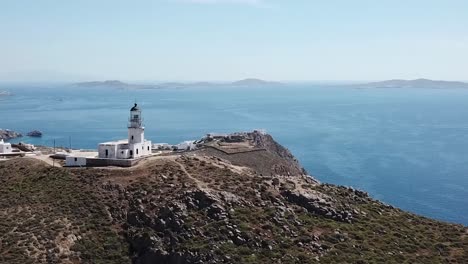 lighthouse on mykonos greece over beach and cliff face