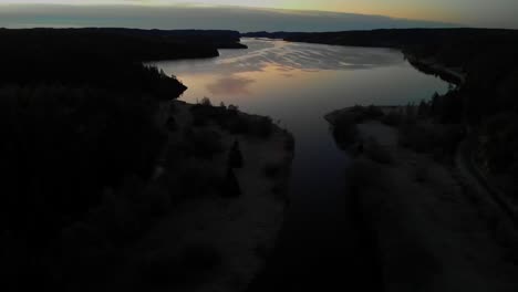 aerial flyover of beautiful lake landscape in sweden, colourful sunset reflection on water