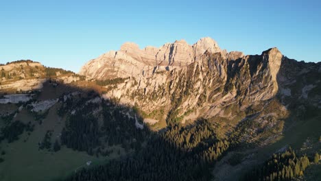 Toma-Aérea-De-Los-Alpes-Suizos-Y-Un-Lago-Situado-En-El-Valle-Cerca-Del-Bosque.