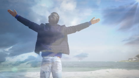 animation of glowing light over man with stretched arms relaxing in nature against blue sky