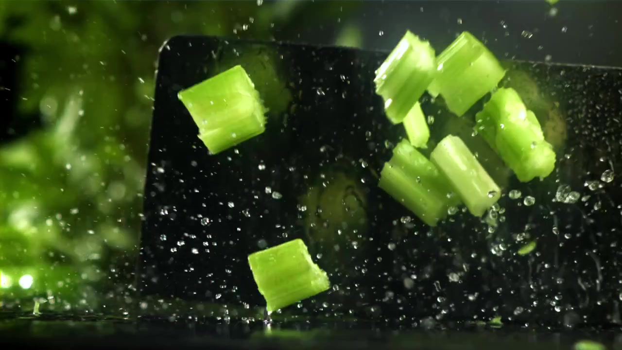 Close-up of Fresh Celery Chopped in Slow Motion with Water Splashes
