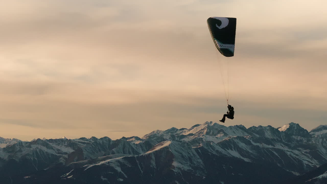 Paragliding over Snowy Mountains at Sunset