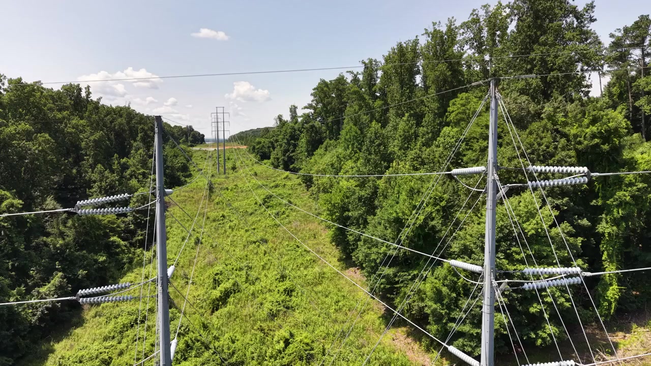 High-voltage transmission corridor near Chattanooga, Tennessee, United States, revealing steel monopoles, polymer insulators, overhead conductors, forest right-of-way and utility easement drone ascent