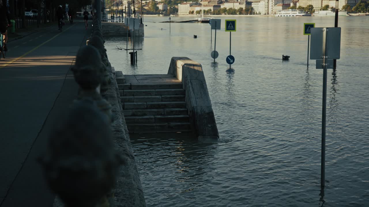 Staircase submerged in floodwater along the Danube River, surrounded by street signs