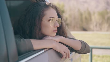 Una-Mujer-Con-Elegantes-Gafas-Amarillas-Se-Asoma-Por-La-Ventanilla-Abierta-Del-Coche