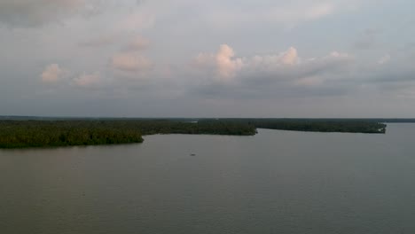 Hermosa-Toma-Aérea-De-Un-Canal-De-Aguas-Estancadas,-Puesta-De-Sol,-Cocoteros,-Transporte-De-Agua,-Nubes,-Cielo-Dorado