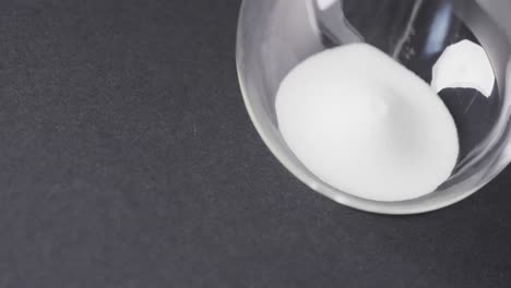 video of close up of hourglass with sand pouring, copy space on black background